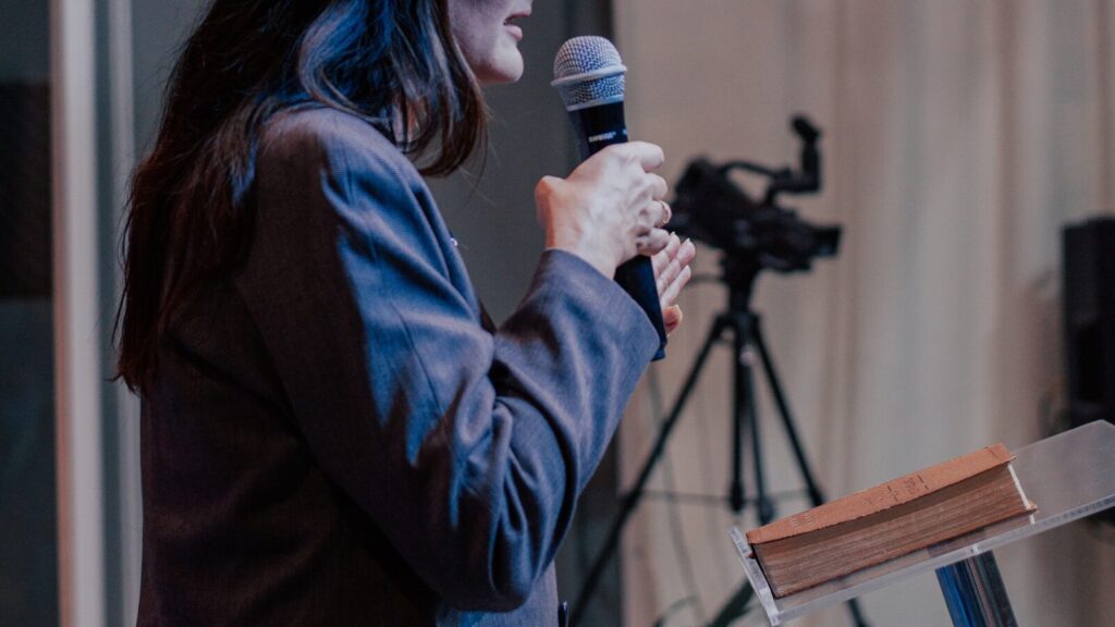 a woman standing at a podium holding a microphone